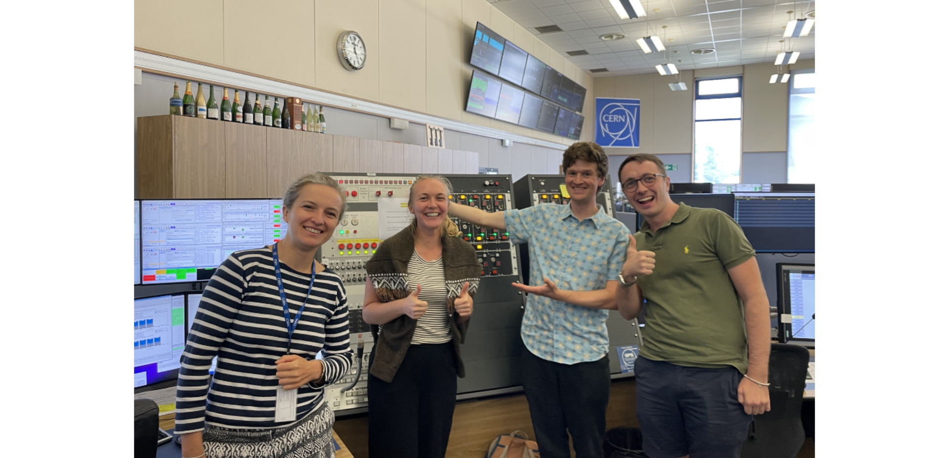 2 men and 2 women smiling in front of buttons and screens